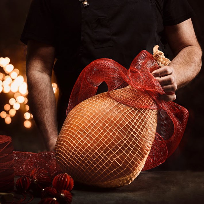 Man holding up a whole Andrew's Christmas Ham